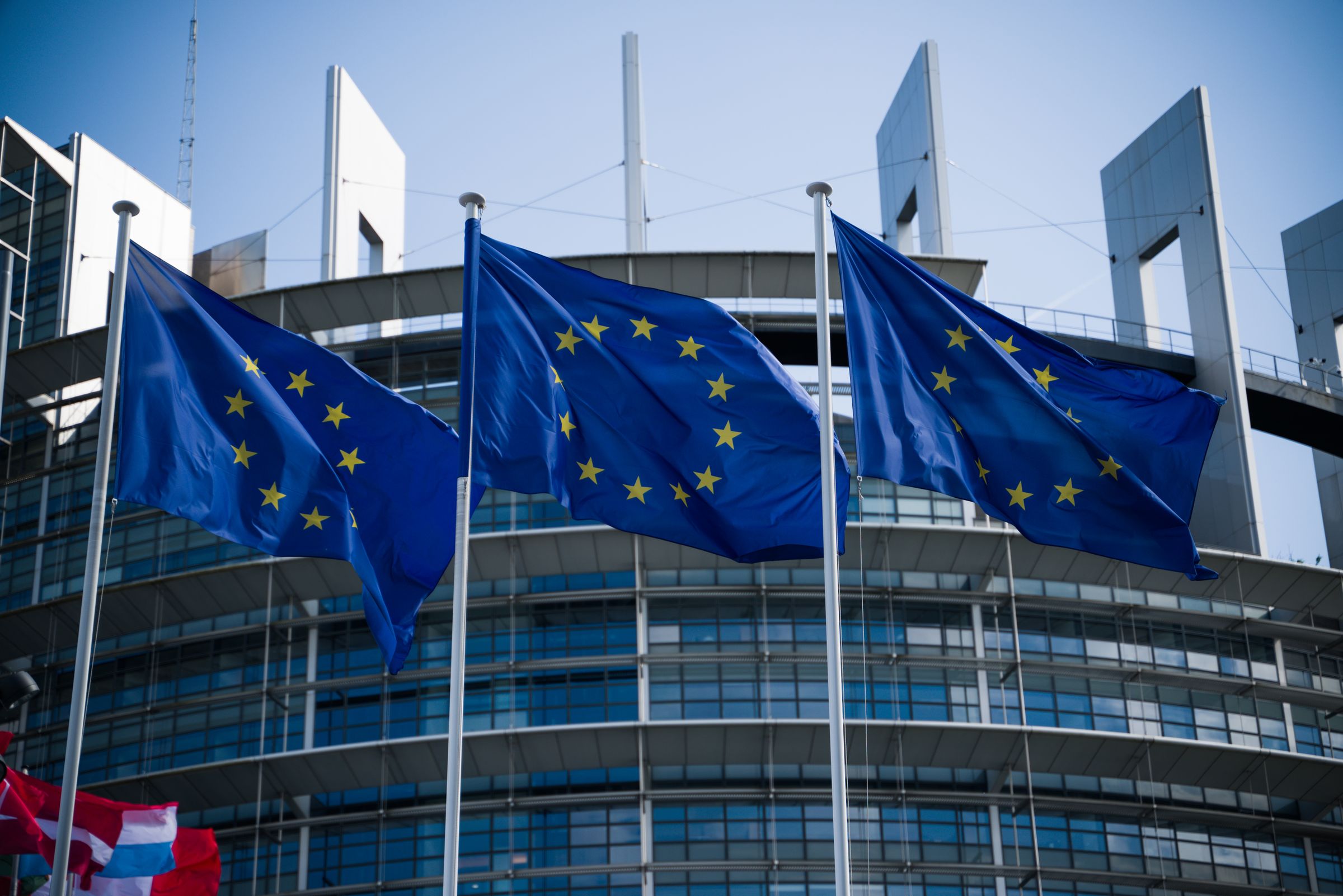 Tre bandiere dell'Unione europea al vento davanti al Parlamento europeo di Strasburgo