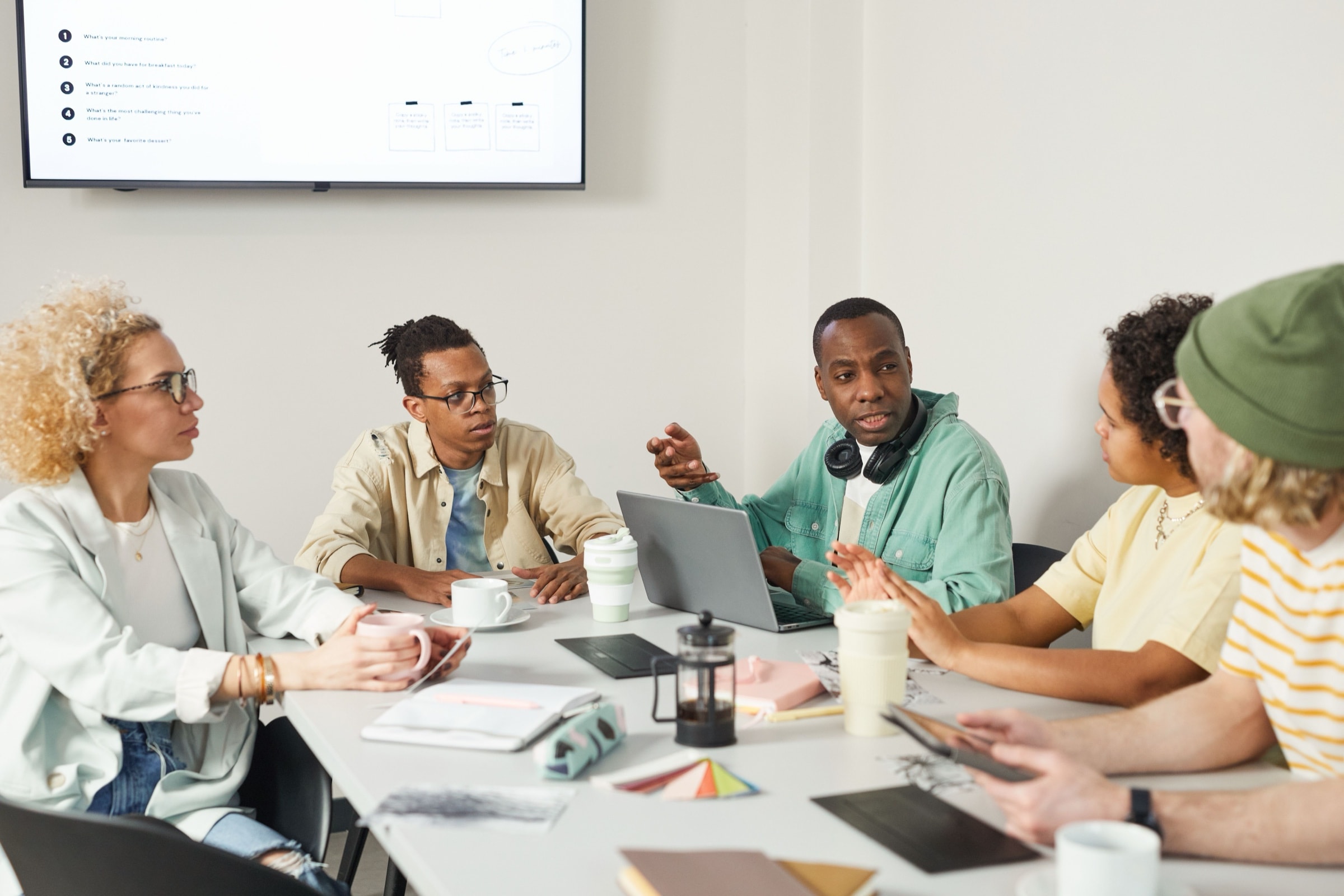 Gruppo di lavoro che discute intorno a un tavolo con computer e documenti