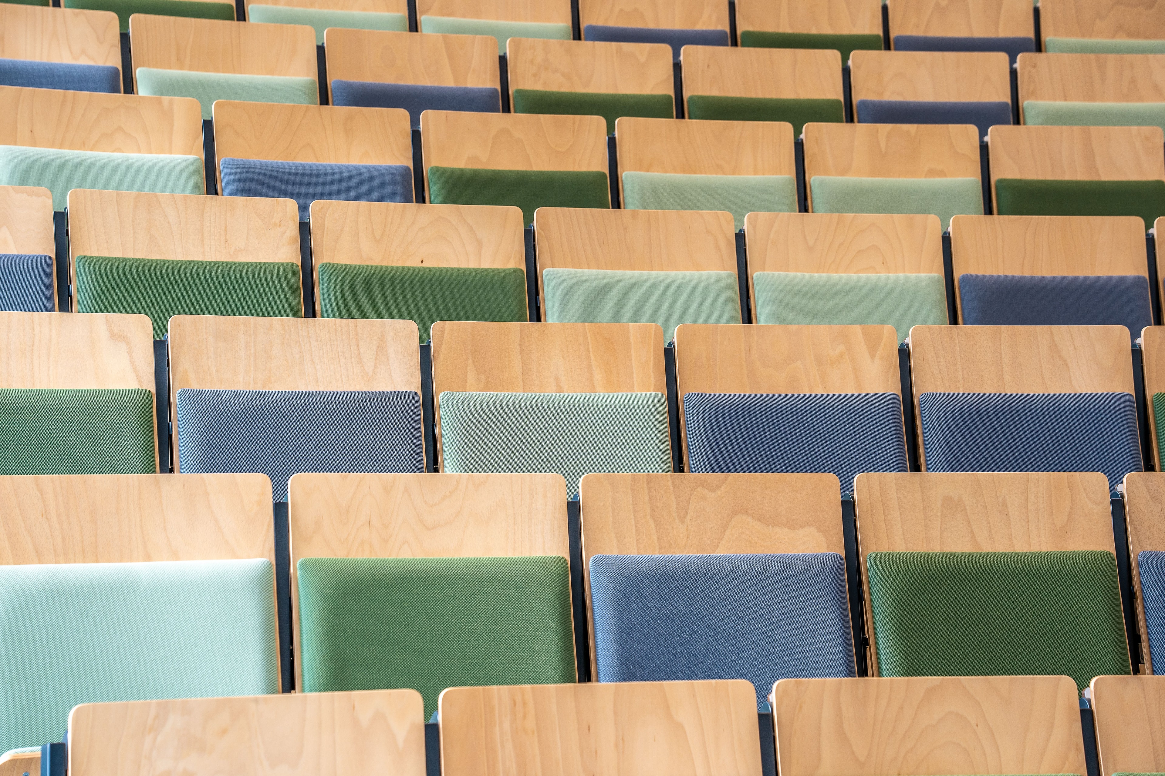 Fila di sedute in legno, verde e blu in un auditorium vuoto