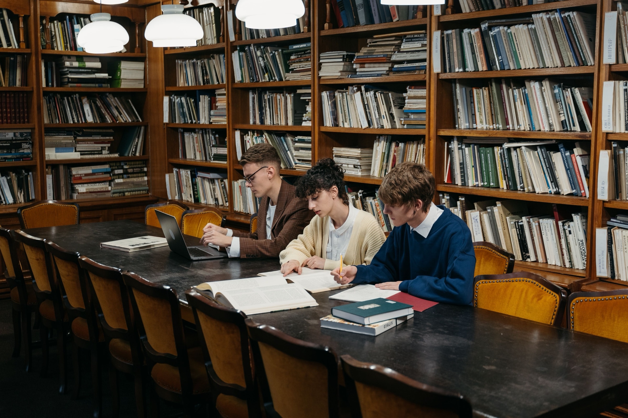 Studenti al lavoro con libri e appunti al tavolo di una biblioteca